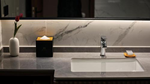 a bathroom counter with a sink and a vase with a flower at VM Hotel in Phnom Penh