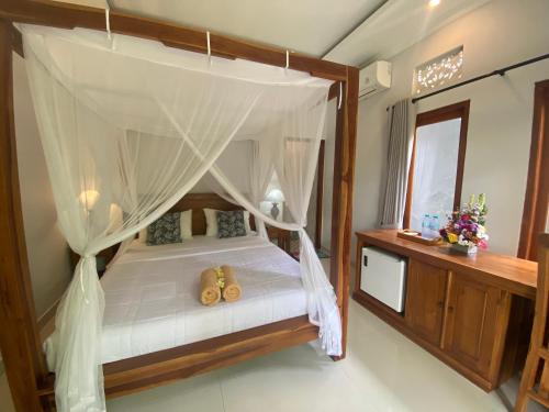 a bedroom with a canopy bed with shoes on it at GUS ARDITYA HOMESTAY in Ubud