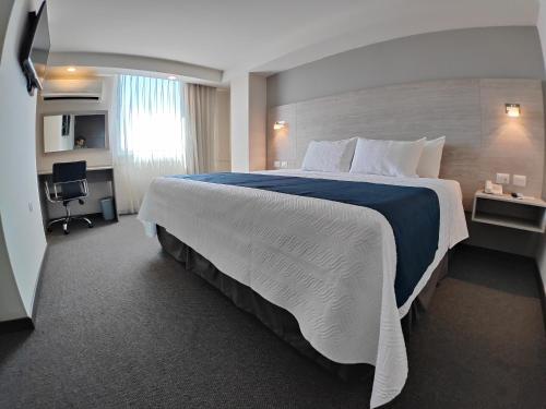 a hotel room with a large bed and a desk at Kasa Hotel & Suites in Irapuato