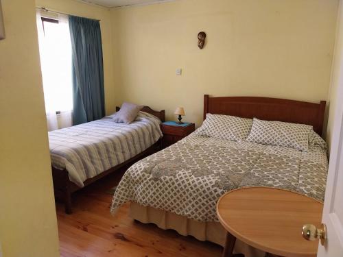 a bedroom with two beds and a table and a window at Paine - Hermosa Parcela de Agrado in Santiago