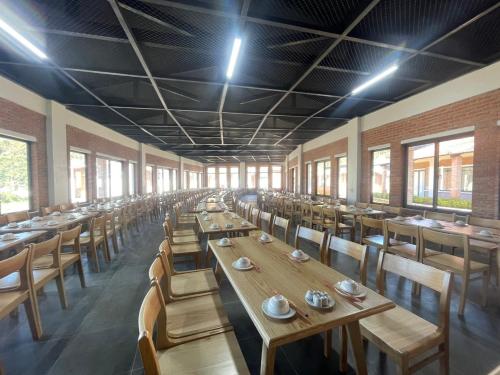 una sala da pranzo con tavoli e sedie in legno e finestre di Mộc Châu Mountain Retreat a Làng Môn
