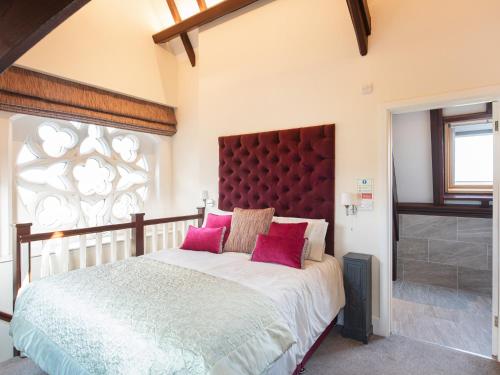 een slaapkamer met een groot bed met roze kussens bij The Old School House 1-uk32061 in Burwarton