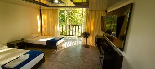 a hotel room with two beds and a balcony at Hotel Campestre Nogal de Cafetal in Quimbaya