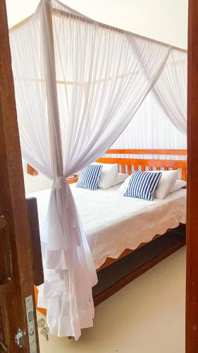 1 dormitorio con cama con dosel y almohadas azules y blancas en Casa Temporada Trancoso, en Trancoso