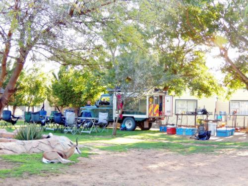 a gazelle laying in the grass next to a truck at Oasis Country Lodge in Klawer