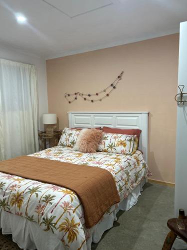 um quarto com uma cama com um cobertor e um papagaio na parede em Jordan Place em Parua Bay