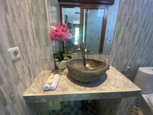 a bathroom with a stone sink and a mirror at GUS ARDITYA HOMESTAY in Ubud