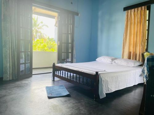 a bedroom with a bed and a window and a door at Galle Side HomeStay in Galle