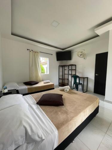 a bedroom with two beds and a window at Hotel Campestre Nogal de Cafetal in Quimbaya
