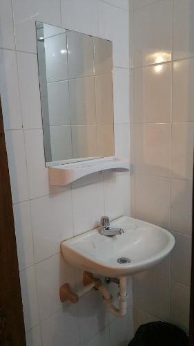 Baño blanco con lavabo y espejo en Hostal Montufar, en Quito
