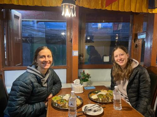 two women sitting at a table with plates of food at HOTEL RUPAKOT AND ROOFTOP RESTAURANT in Bhaktapur