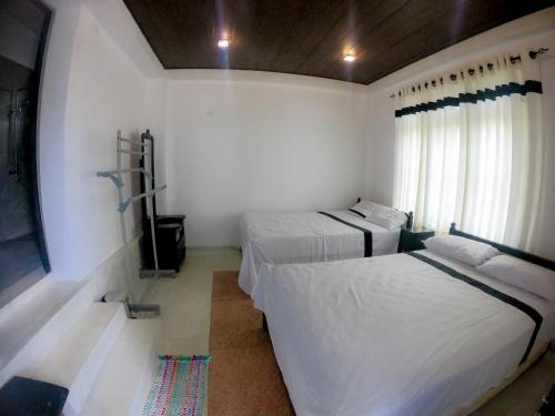 1 dormitorio con 2 camas y ventana en Knuckles Range Bunglow en Kandy