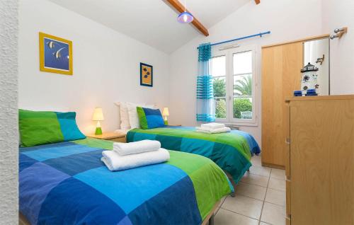 two beds in a room with green and blue at Le Domaine De Vertmarines in Saint-Jean-de-Monts