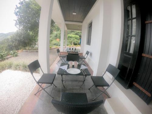 a patio with a table and chairs on a porch at Knuckles Range Bunglow in Kandy