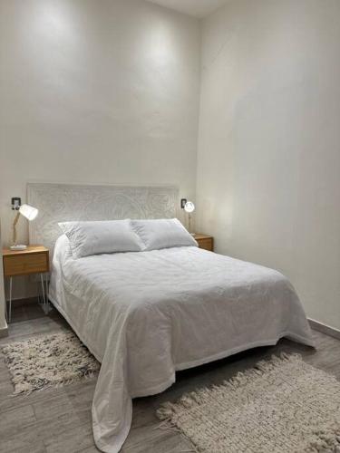 ein weißes Schlafzimmer mit einem Bett und zwei Nachttischen in der Unterkunft Martita House in Clorinda