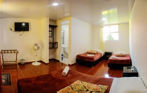 a living room with two beds and a tv at Hotel Campestre Nogal de Cafetal in Quimbaya