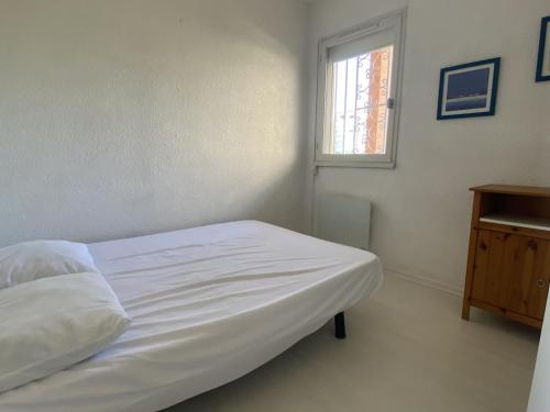 un lit blanc dans une chambre avec une fenêtre dans l'établissement Appartement 2P rénové, vue mer, parking, plage en face - FR-1-338-530, à Sète