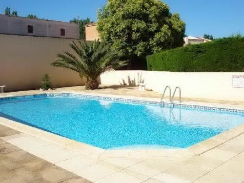 une grande piscine bleue à côté d'un mur blanc dans l'établissement Appartement Climatisé avec Terrasse, Piscine et Parking, à 700m de la Plage à Argelès-sur-Mer - FR-1-776-4, à Argelès-sur-Mer
