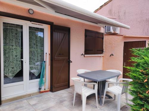 une terrasse avec une table et des chaises à côté d'une maison dans l'établissement Pavillon Climatisé Près de la Plage avec Terrasse, Parking et Confort Moderne - FR-1-776-7, à Argelès-sur-Mer