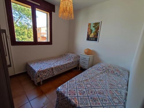 une chambre avec deux lits et une fenêtre dans l'établissement Duplex 6 pers. proche plage, terrasse, parking, animaux admis - FR-1-776-23, à Argelès-sur-Mer
