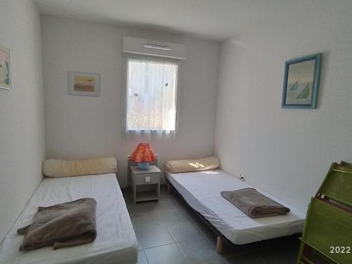 deux lits dans une chambre avec une fenêtre dans l'établissement Appartement 4 pers, piscine, terrasse avec BBQ, parking, proche plage – Argelès-sur-Mer - FR-1-776-27, à Argelès-sur-Mer