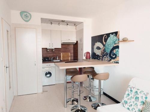 une cuisine avec un comptoir et des tabourets dans une pièce dans l'établissement Appartement cosy 2P à 200m de la plage avec parking - 4 pers, Argelès-sur-Mer - FR-1-776-28, à Argelès-sur-Mer