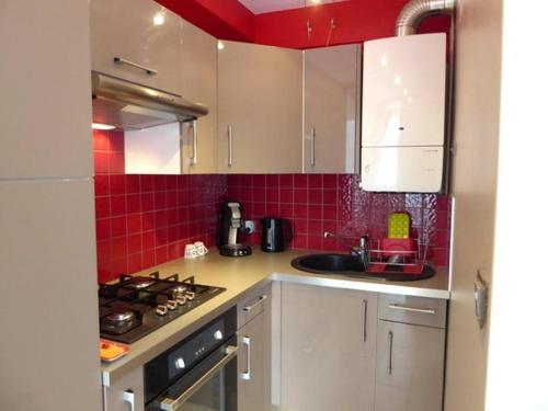 - une cuisine avec des placards blancs et du carrelage rouge dans l'établissement T2 rénové, climatisé, proche plage, terrasse, parking, animaux OK - FR-1-776-20, à Argelès-sur-Mer
