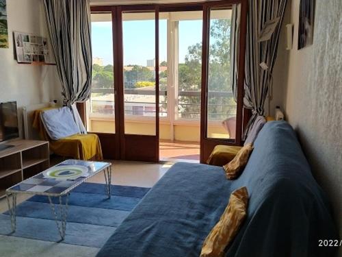 un salon avec un canapé bleu et une table dans l'établissement Appartement climatisé 2 pièces avec parking, animaux admis, 500m de la plage - FR-1-776-38, à Argelès-sur-Mer