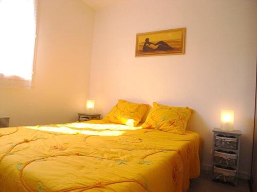 1 dormitorio con 1 cama con sábanas amarillas y 2 velas en Appartement Argelès-sur-Mer, 2 pièces, 4 personnes - FR-1-776-43, en Argelès-sur-Mer