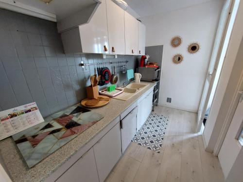 une cuisine avec des armoires blanches et un comptoir dans l'établissement Appartement avec WIFI, climatisation et parking - 400m de la plage - FR-1-776-15, à Saint-Cyprien