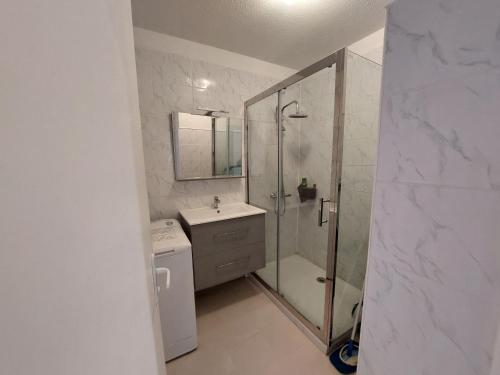 une salle de bain blanche avec une douche et un lavabo dans l'établissement Appartement avec WIFI, climatisation et parking - 400m de la plage - FR-1-776-15, à Saint-Cyprien