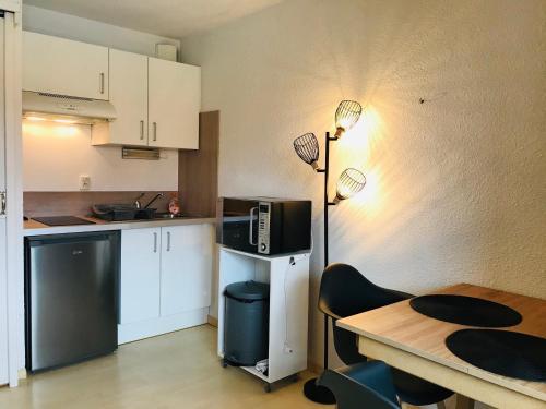une petite cuisine avec une table et un micro-ondes dans l'établissement Studio Cabine à 400m Plage avec Piscine, Parking Privé, Proche Commerces à Argelès-sur-Mer - FR-1-776-16, à Argelès-sur-Mer