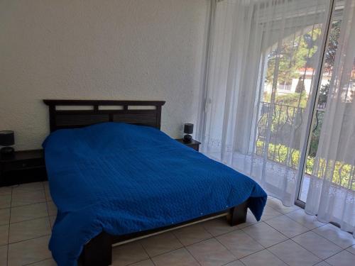 une chambre avec un lit bleu et une fenêtre dans l'établissement Appartement 2 pièces avec piscine, parking privé, à 400m de la plage - 4 personnes - FR-1-776-46, à Argelès-sur-Mer