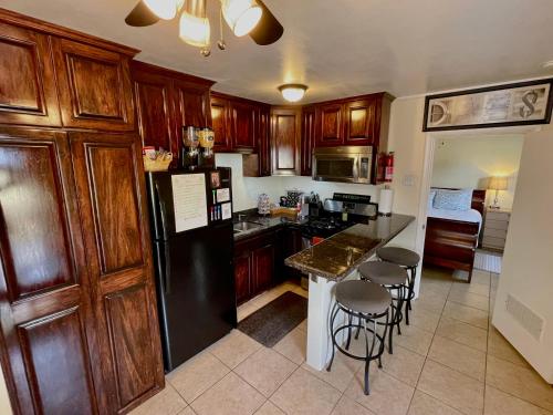 a kitchen with wooden cabinets and a black refrigerator at 3Mins.Airport/Fort Bliss-Pet Friendly-Washer/Dryer in El Paso