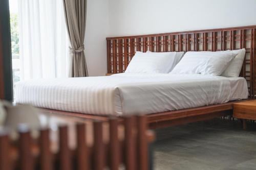 uma cama com cabeceira em madeira e almofadas brancas em Long Set Resort em Koh Rong Island