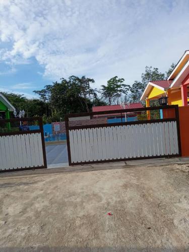 una cerca blanca frente a un parque infantil en Maksu homestay en Kuala Nerang
