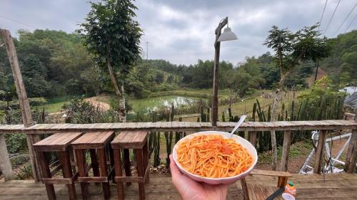a person holding a bowl of carrots on a wooden table at Vu Glamping in Hue