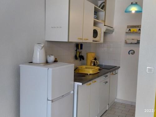 La cuisine est équipée d'un réfrigérateur blanc et de placards blancs. dans l'établissement Studio Climatisé Port Argelès: 3 Pers, Loggia, Parking, Plage & Commerces à Proximité - FR-1-776-62, à Argelès-sur-Mer