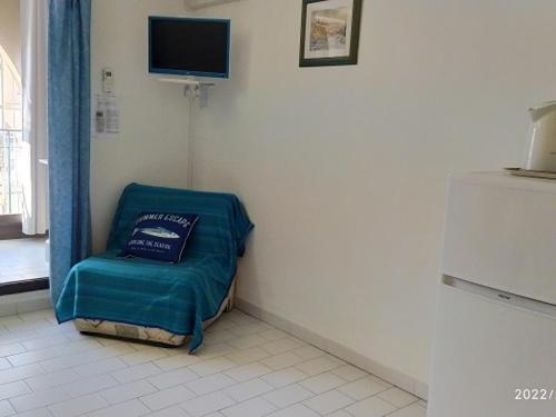 Cette chambre dispose d'une chaise verte et d'une télévision murale. dans l'établissement Studio Climatisé Port Argelès: 3 Pers, Loggia, Parking, Plage & Commerces à Proximité - FR-1-776-62, à Argelès-sur-Mer