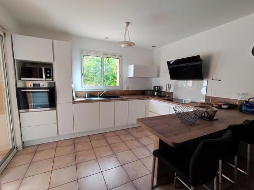 cocina con armarios blancos y mesa de madera en Villa Argelès-sur-Mer, 4 pièces, 6 personnes - FR-1-776-67, en Argelès-sur-Mer