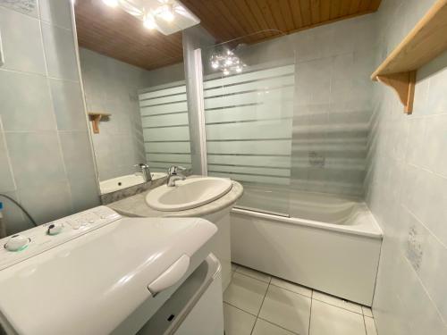 une salle de bain blanche avec un lavabo et une baignoire dans l'établissement Maison Type 2 avec Piscine Chauffée, Tennis et Proximité Bord de Mer à Brétignolles - FR-1-231-306, à Bretignolles-sur-Mer