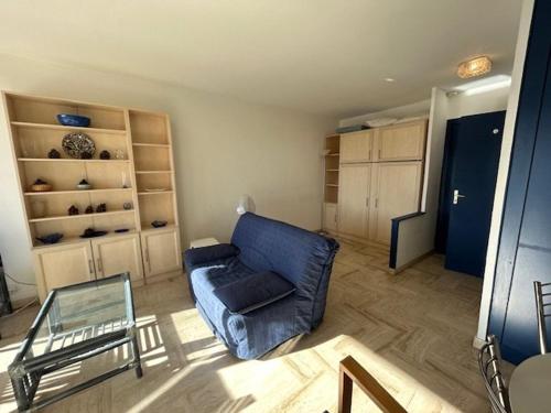 un salon avec un canapé bleu et une table en verre dans l'établissement Studio avec piscine, balcon, parking à Mandelieu-la-Napoule - FR-1-609-92, à Mandelieu-la-Napoule