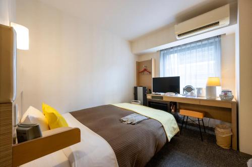 Una habitación de hotel con una cama y un escritorio con una computadora. en Hotel 1-2-3 Takasaki, en Takasaki