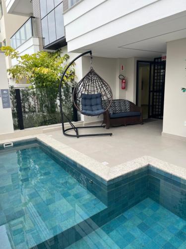 - une balançoire assise sur une terrasse à côté d'une piscine dans l'établissement Apartamento com piscina a 100 metros da praia, à Governador Celso Ramos