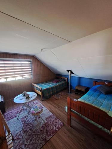 Camera mansardata con 2 letti e un tavolo. di hospedaje a Puerto Varas