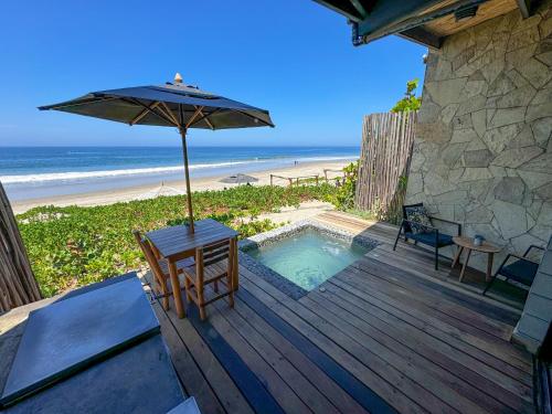 een houten terras met een parasol en een tafel en stoelen bij DIEM Vichayito Beachfront Eco-Luxury in Vichayito