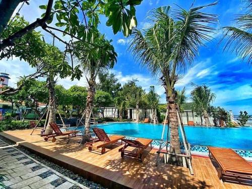 una piscina en el complejo con sillas y palmeras en An Hoa Residence, en Long Hai