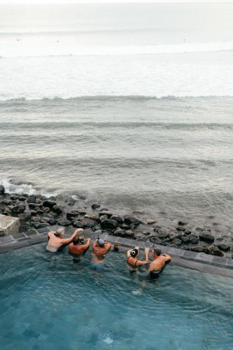 a group of men standing in the water in a swimming pool at Bombora Medewi in Pulukan