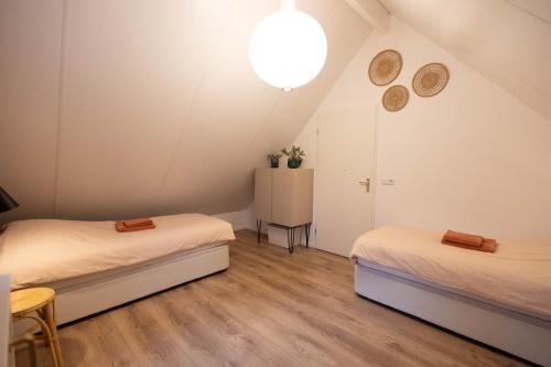 Cette chambre comprend deux lits, une table et une lampe. dans l'établissement Vakantiehuis Vliegend Hert Veluwe, à Nunspeet