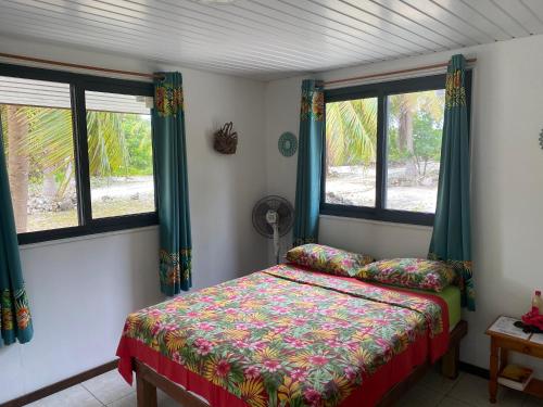 sypialnia z łóżkiem i 2 oknami w obiekcie KoriKori House Fakarava w mieście Rotoava